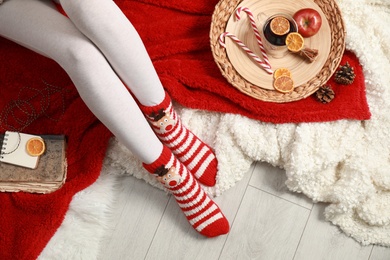 Photo of Woman and cup of hot winter drink on floor at home, top view