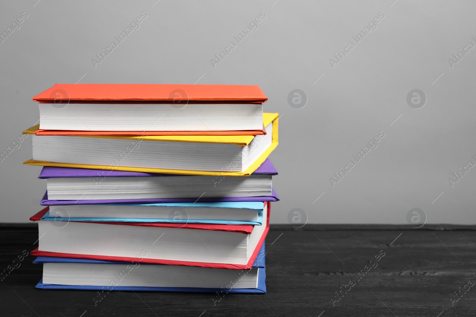 Photo of Different books on black wooden table against gray background, space for text