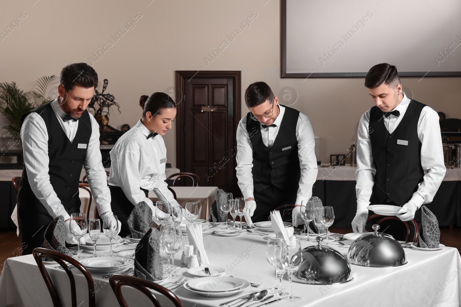 Photo of People setting table during professional butler courses in restaurant