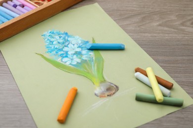 Photo of Beautiful drawing of blue hyacinth and pastels on wooden table
