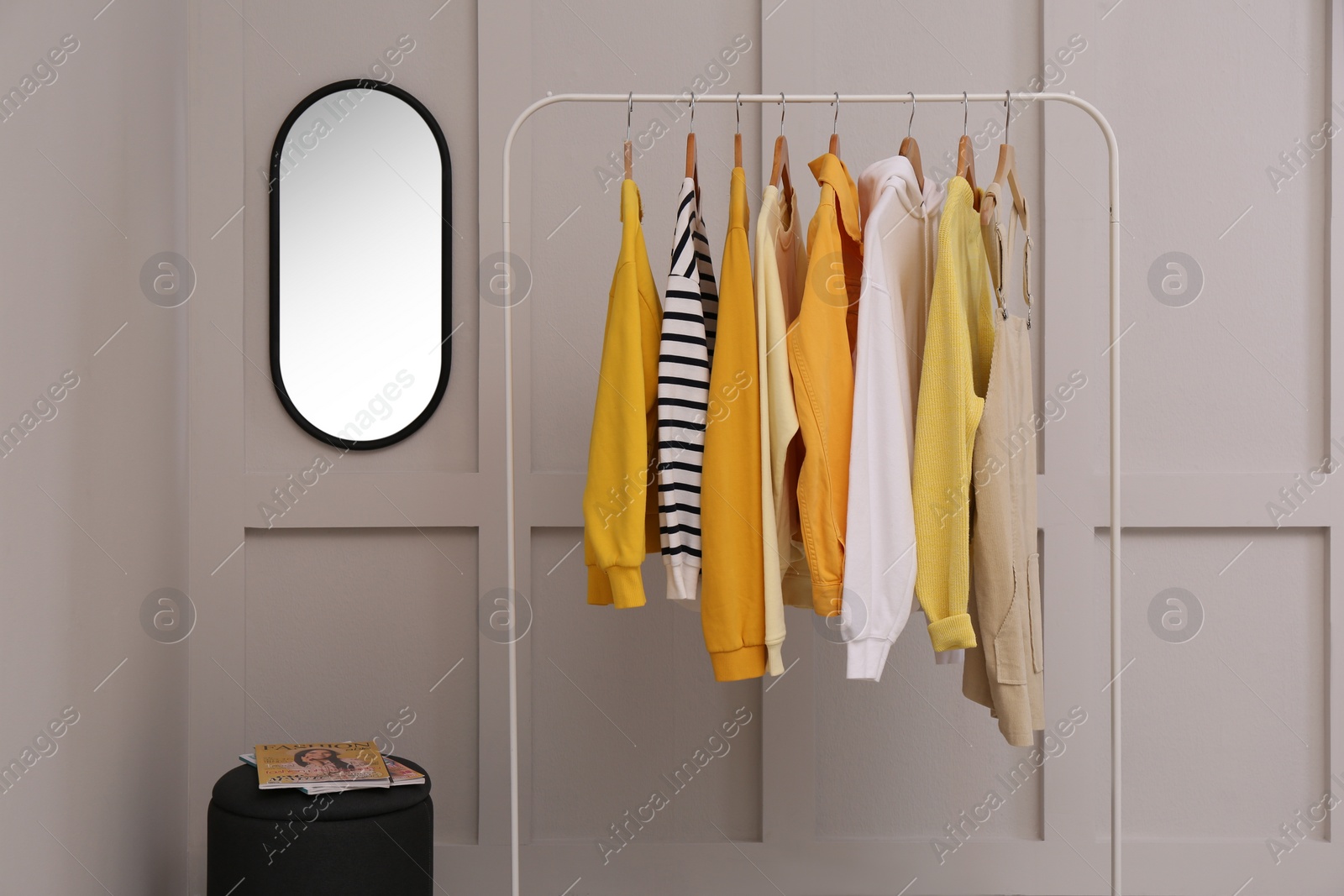 Photo of Rack with stylish women's clothes near light wall