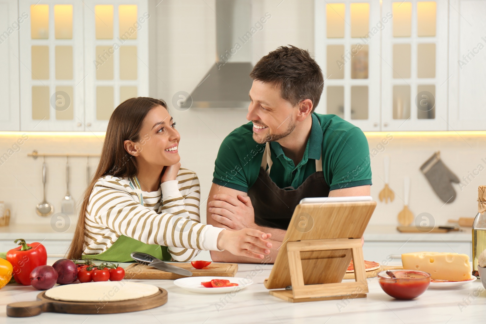 Photo of Couple watching online cooking course via tablet in kitchen