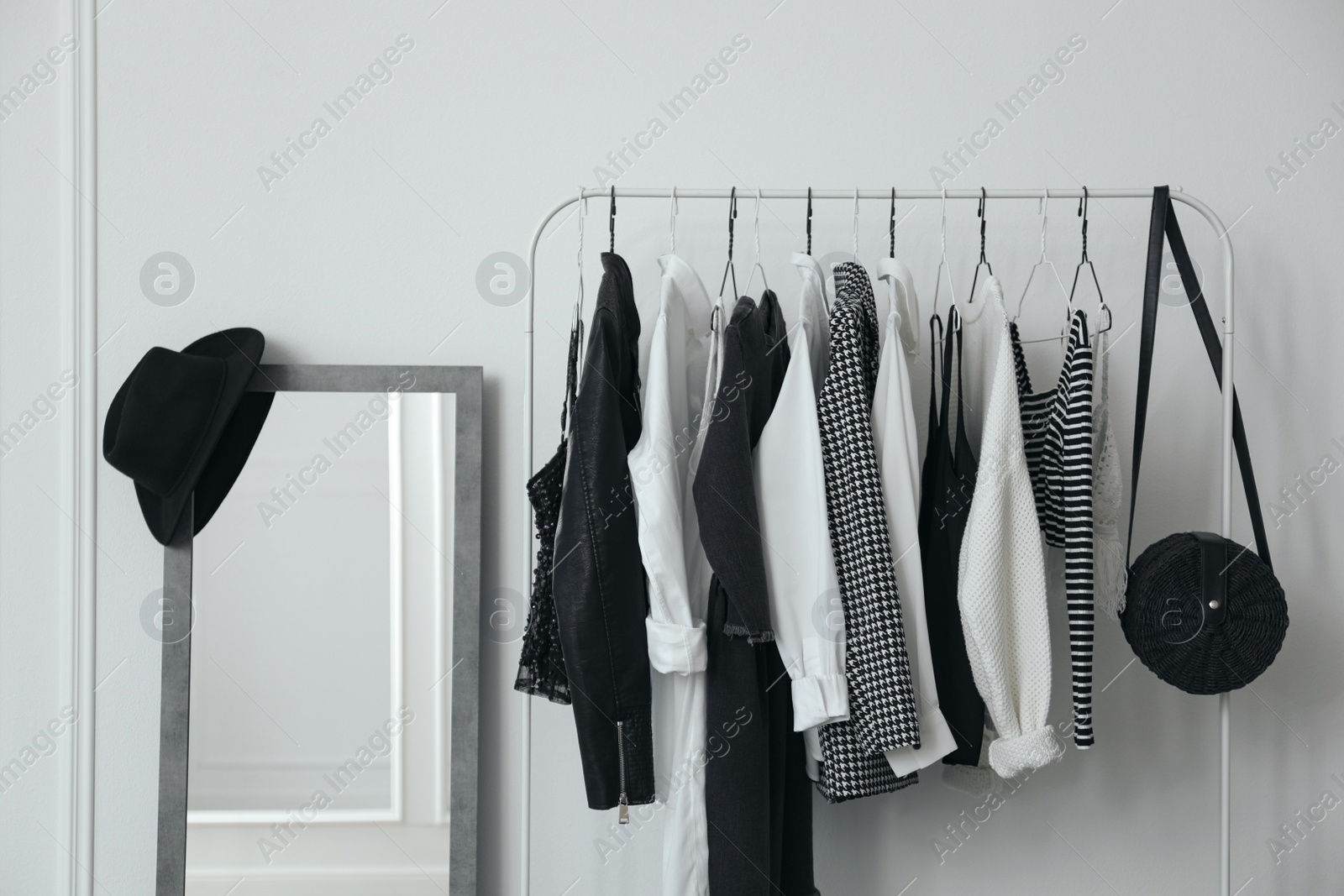 Photo of Rack with stylish clothes near white wall in dressing room