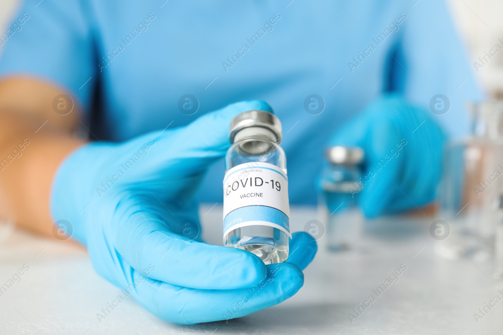 Photo of Doctor with coronavirus vaccine at table in laboratory, closeup