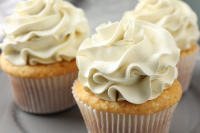 Tasty cupcakes with vanilla cream on table, closeup