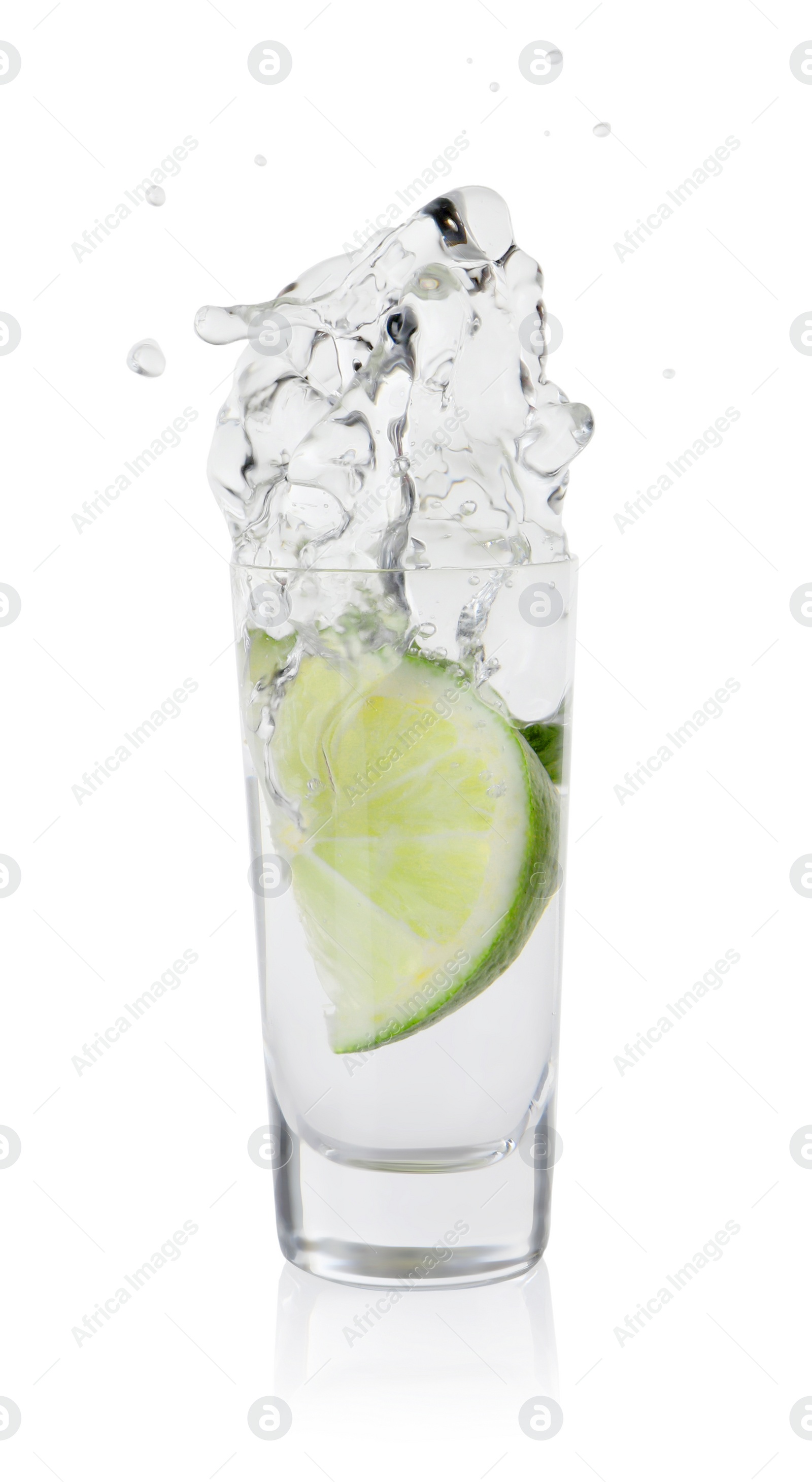 Photo of Vodka splashing out of shot glass with lime on white background