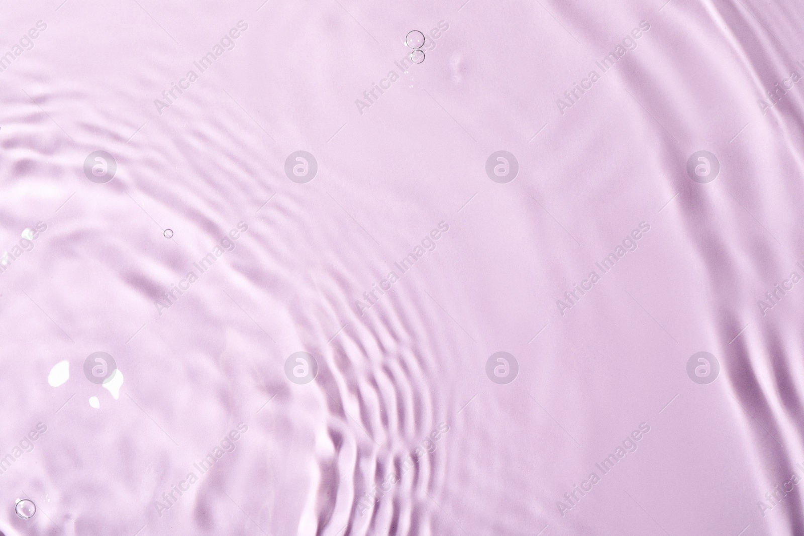 Photo of Closeup view of water with rippled surface on violet background