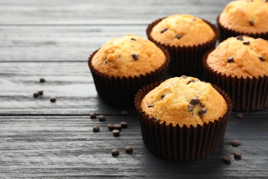 Photo of Delicious freshly baked muffins with chocolate chips on dark gray table, closeup