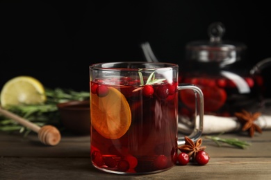 Photo of Tasty hot cranberry tea with rosemary and lemon on wooden table