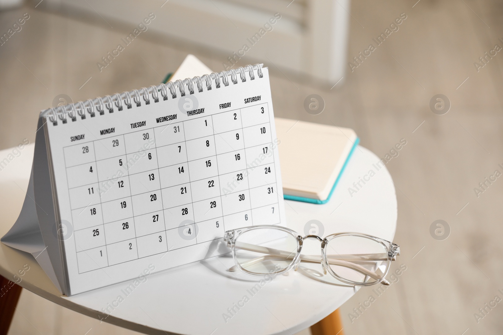 Photo of Paper calendar, notebook and glasses on white table indoors