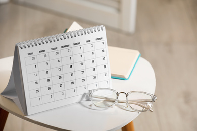 Photo of Paper calendar, notebook and glasses on white table indoors