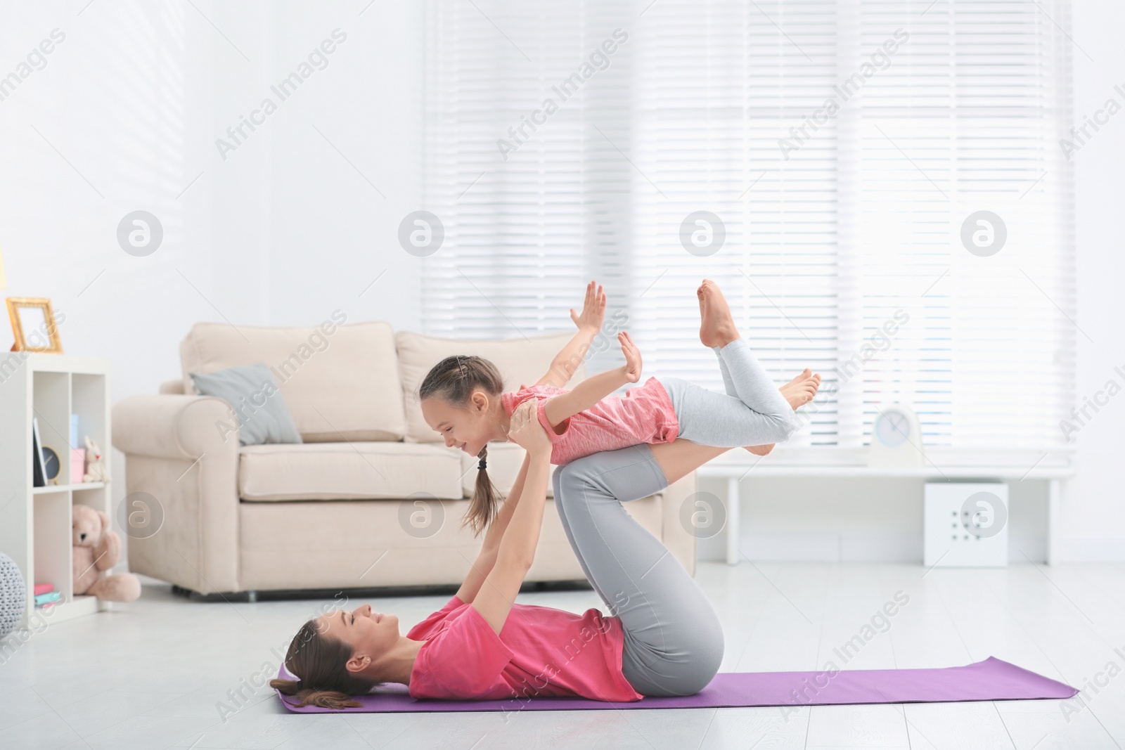 Photo of Young mother with little daughter practicing yoga at home