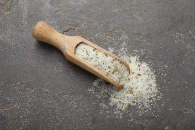 Photo of Wooden scoop with natural herb salt on grey table, top view