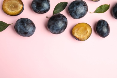 Photo of Delicious ripe plums on pink background, flat lay. Space for text