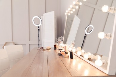 Modern mirror with light bulbs on dressing table in makeup room