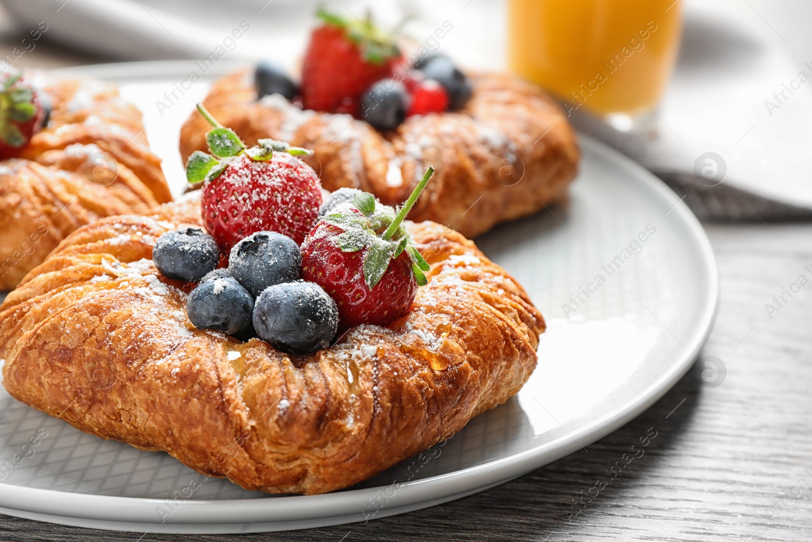 Photo of Fresh delicious puff pastry with sweet berries on wooden table, closeup