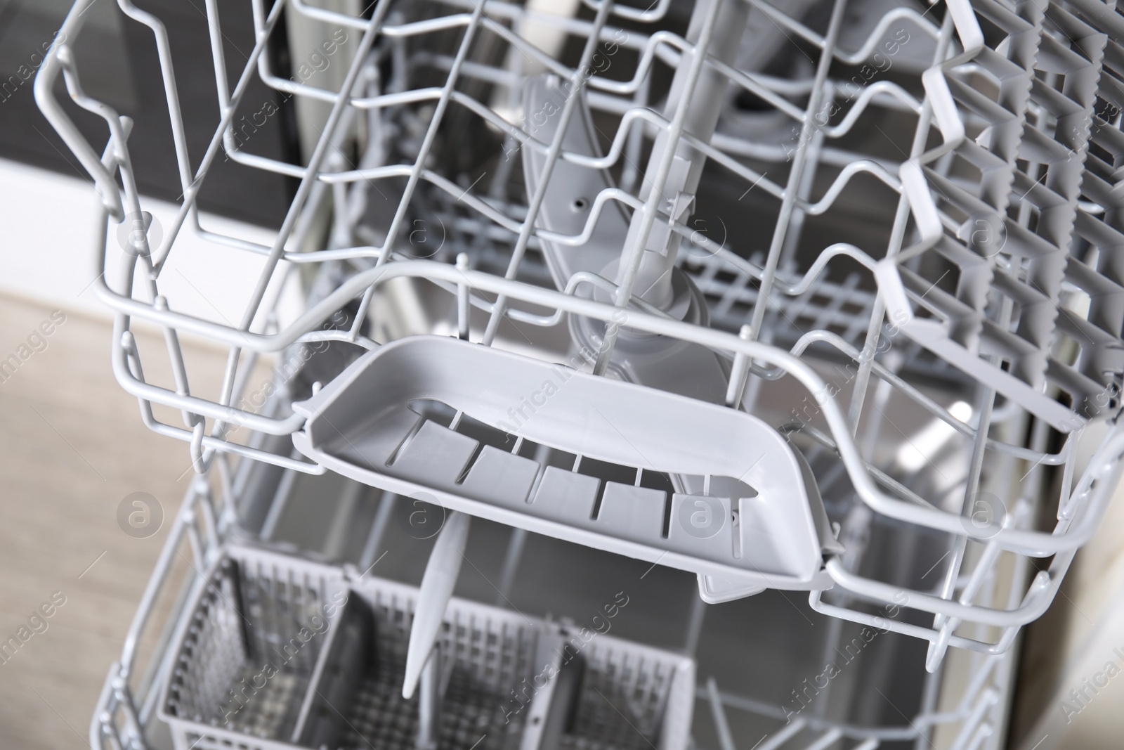 Photo of Open clean empty dishwasher in kitchen, closeup