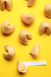 Many tasty fortune cookies with predictions on yellow background, flat lay. Space for text