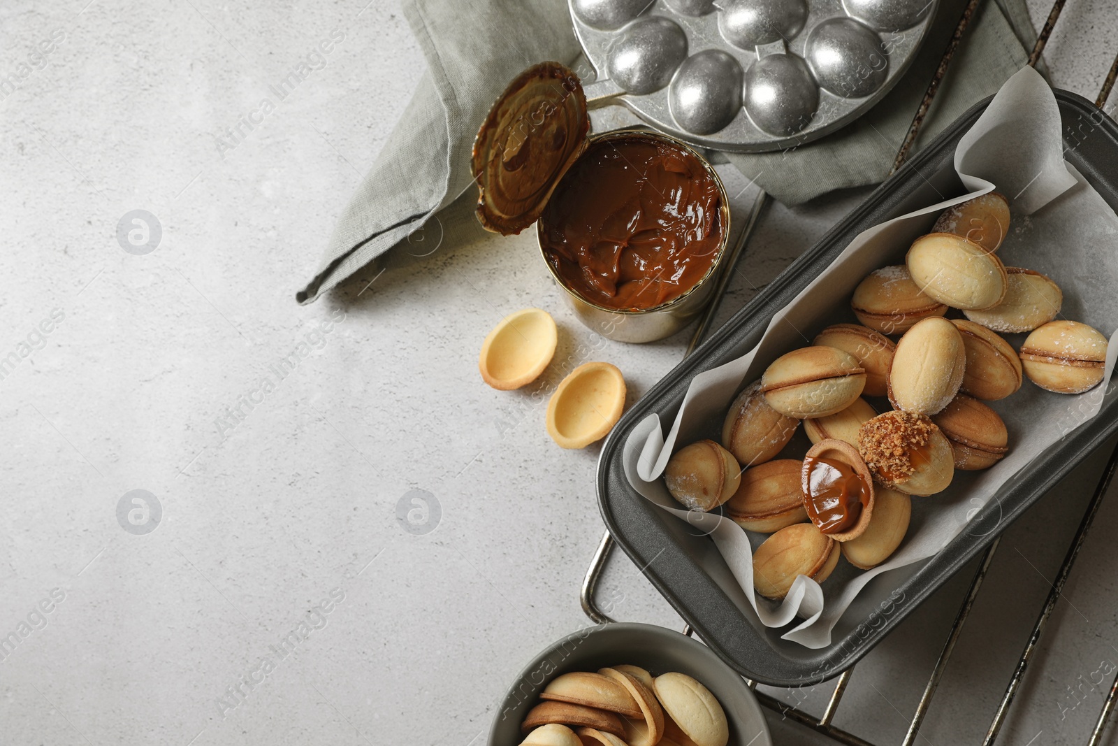 Photo of Delicious walnut shaped cookies with condensed milk on grey table, flat lay. Space for text