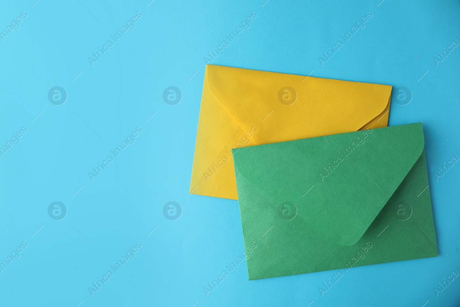 Photo of Colorful paper envelopes on light blue background, flat lay. Space for text