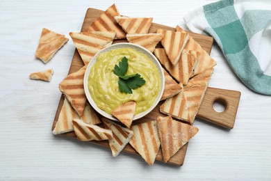 Photo of Delicious pita chips and hummus on white wooden table, flat lay