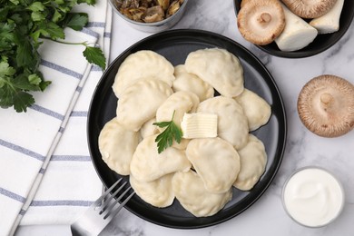 Photo of Delicious dumplings (varenyky) with mushrooms, parsley, butter and sour cream served on white marble table, flat lay
