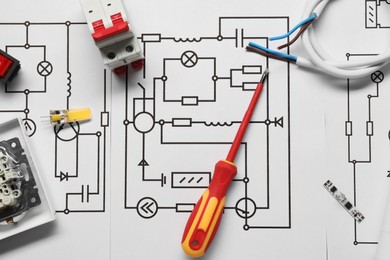 Photo of Different electrician's equipment and screwdriver on wiring diagram, flat lay