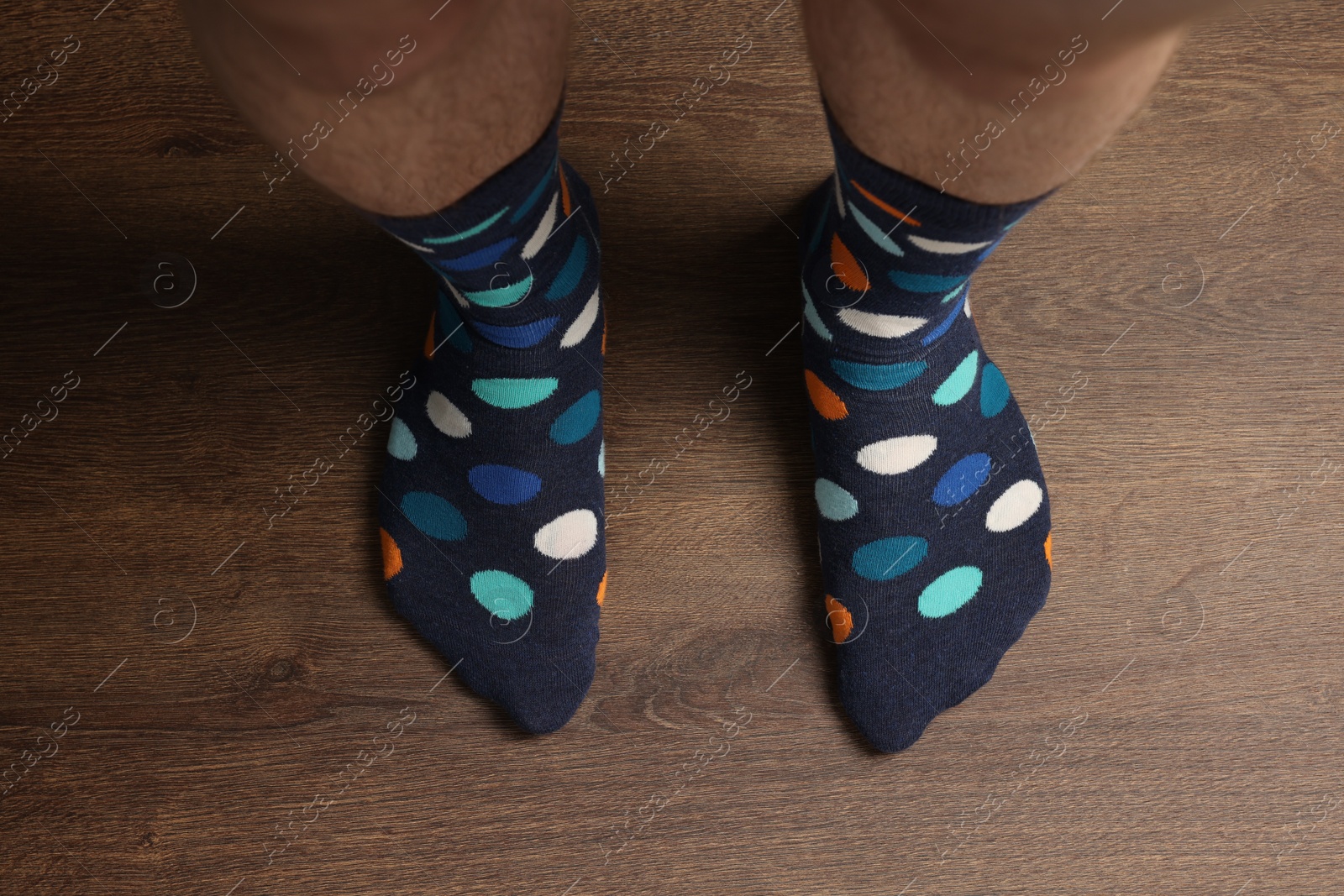 Photo of Man in stylish colorful socks standing on wooden floor, top view