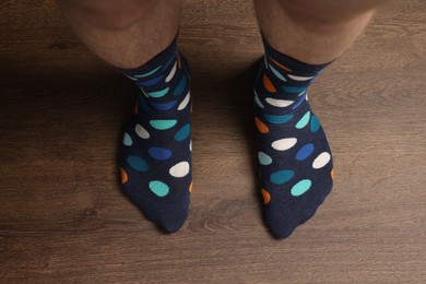 Photo of Man in stylish colorful socks standing on wooden floor, top view