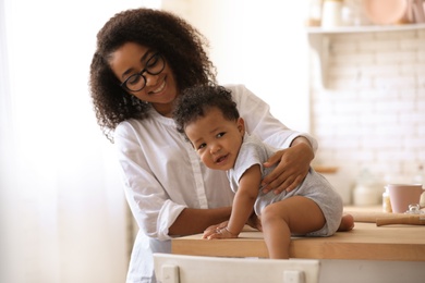 Photo of African-American woman with her baby in kitchen. Happiness of motherhood