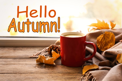 Hello Autumn card. Cup of hot drink, golden leaves and scarf on wooden windowsill