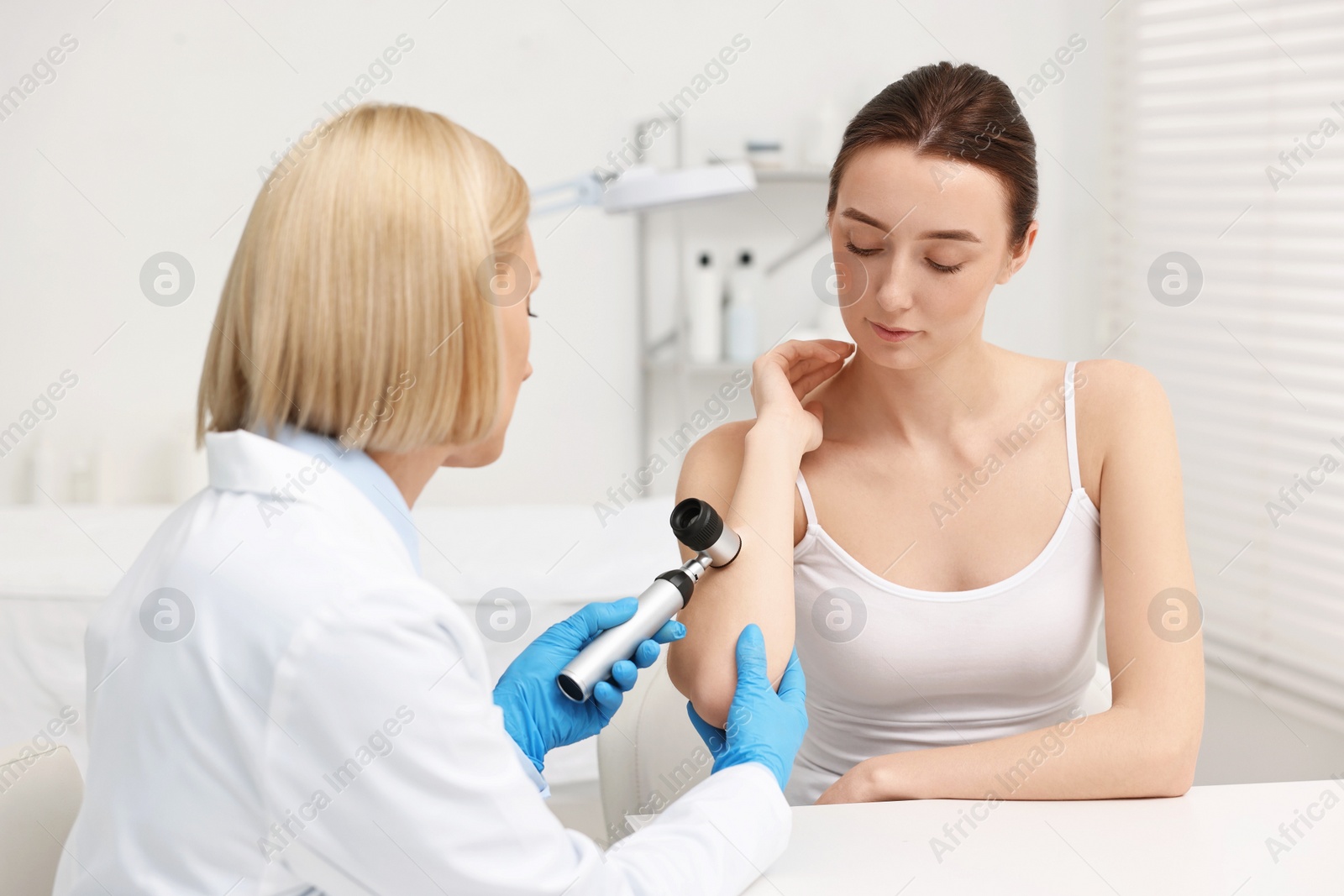 Photo of Dermatologist with dermatoscope examining patient in clinic