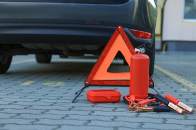 Emergency warning triangle and safety equipment near car, space for text