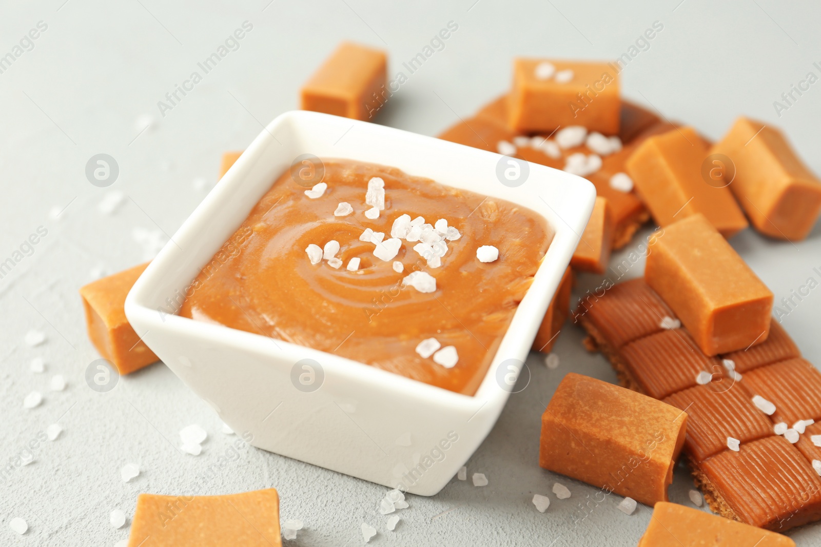 Photo of Gravy boat with salted caramel sauce and candies on table