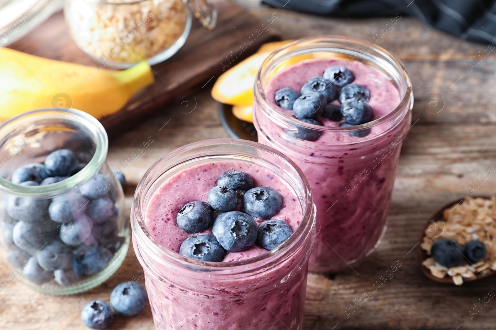 Photo of Jars with blueberry smoothies on table, closeup