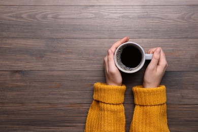 Photo of Woman with cup of coffee at wooden table, top view. Space for text