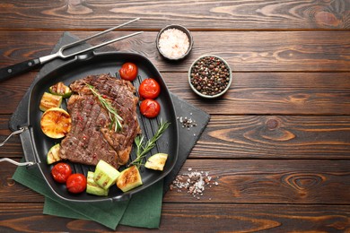 Photo of Delicious grilled beef steak and vegetables served on wooden table, flat lay. Space for text