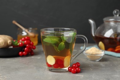 Photo of Glass cup of immunity boosting drink and ingredients on grey table