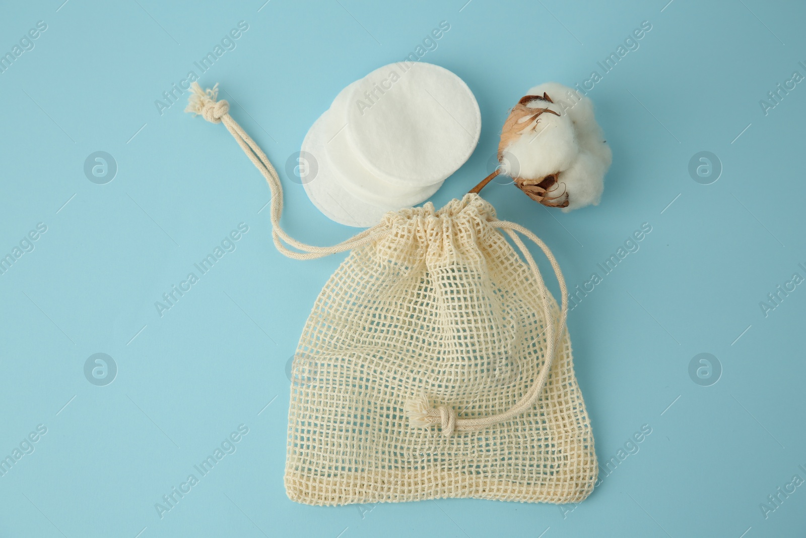 Photo of Bag, cotton pads and flower on light blue background