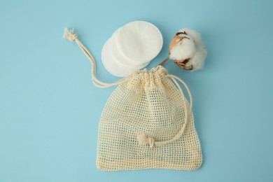 Photo of Bag, cotton pads and flower on light blue background