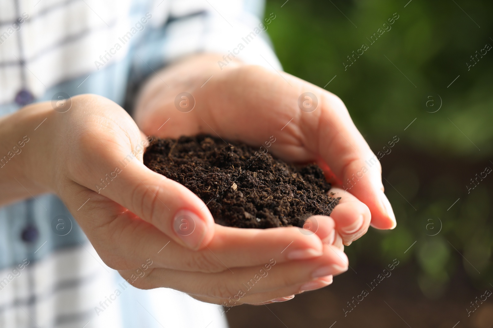 Photo of Woman with handful of soil outdoors, closeup