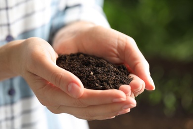 Photo of Woman with handful of soil outdoors, closeup