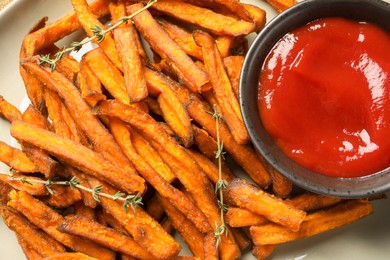 Photo of Sweet tasty potato fries and ketchup on plate, closeup