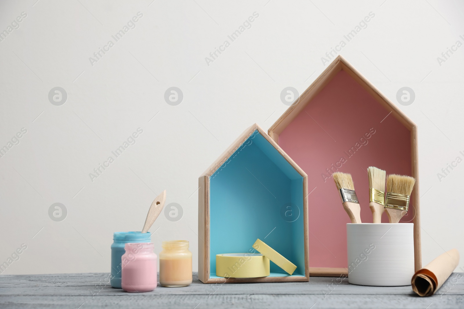 Photo of Brush with paint and wooden houses on grey table