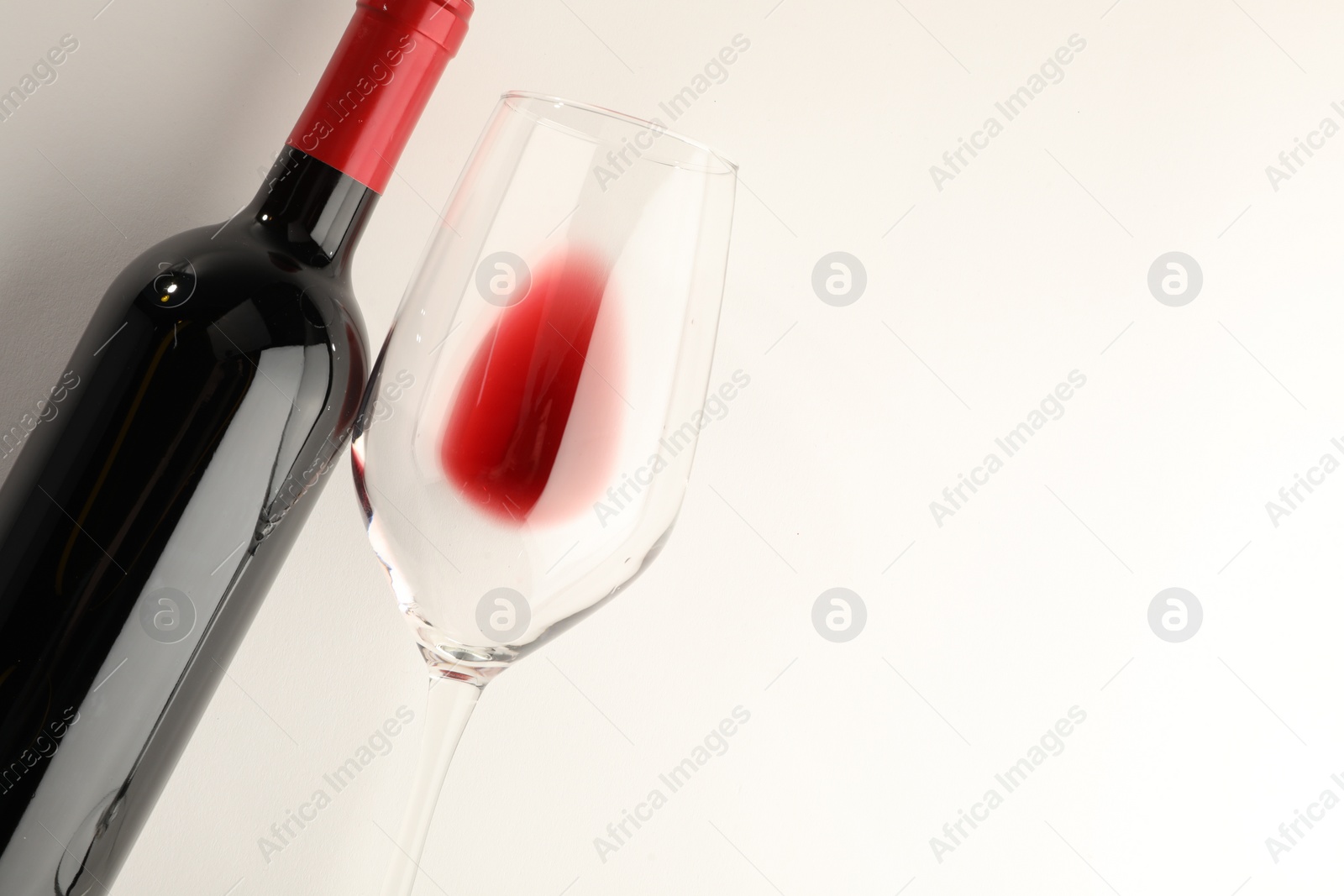 Photo of Bottle of expensive red wine and wineglass on white background, top view. Space for text