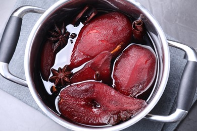 Photo of Tasty red wine poached pears and spices in pot on grey table, top view