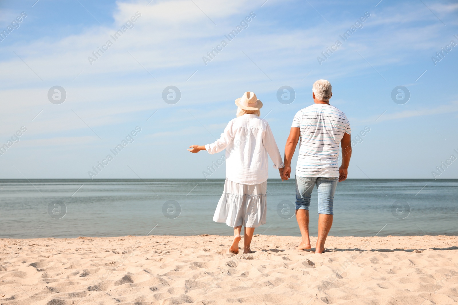 Photo of Mature couple spending time together on sea beach, back view