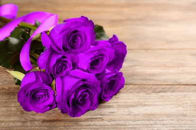 Image of Violet roses on wooden table, space for text. Funeral attributes