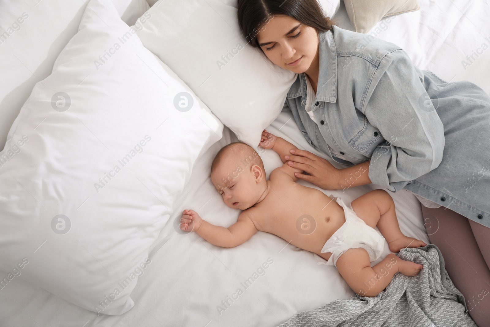 Photo of Mother with her cute baby sleeping on bed, above view