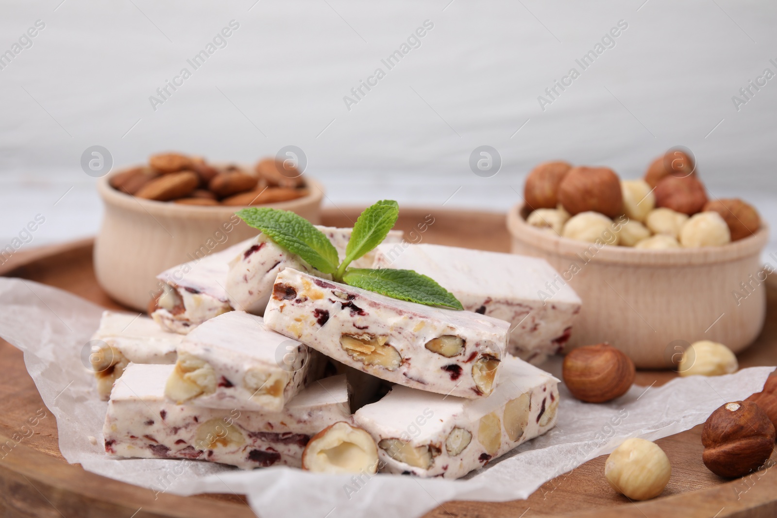 Photo of Pieces of delicious nougat and nuts on wooden board, closeup